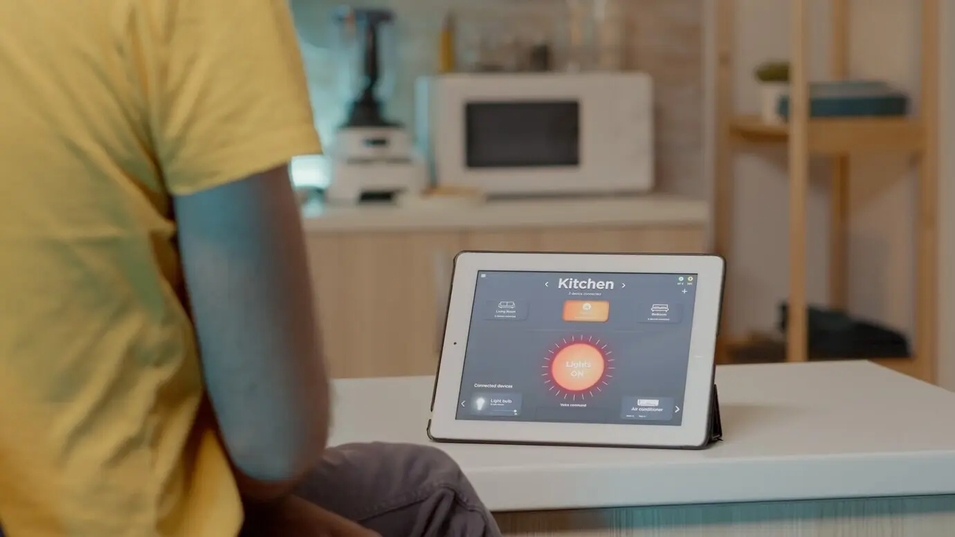 Молодой мужчина использует приложение умного дома на цифровом планшете и голосовую команду, чтобы включить свет.